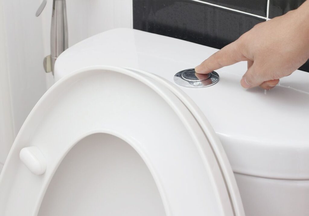 Pessoa acionando descarga do vaso sanitário
