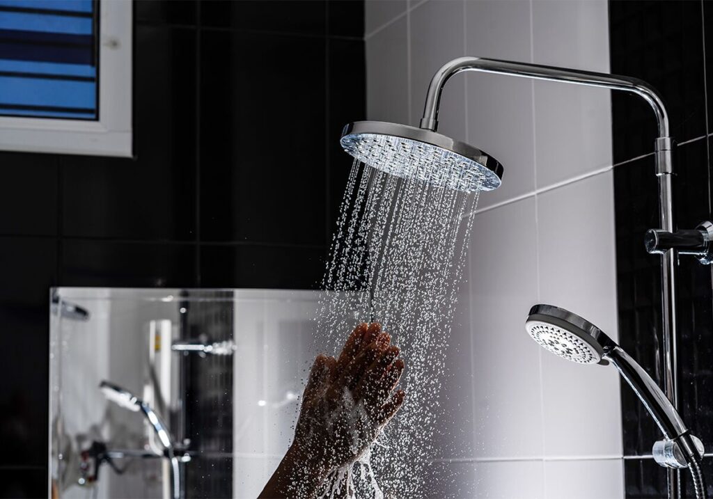 Chuveiro moderno com água caindo e mão segurando a ducha.
